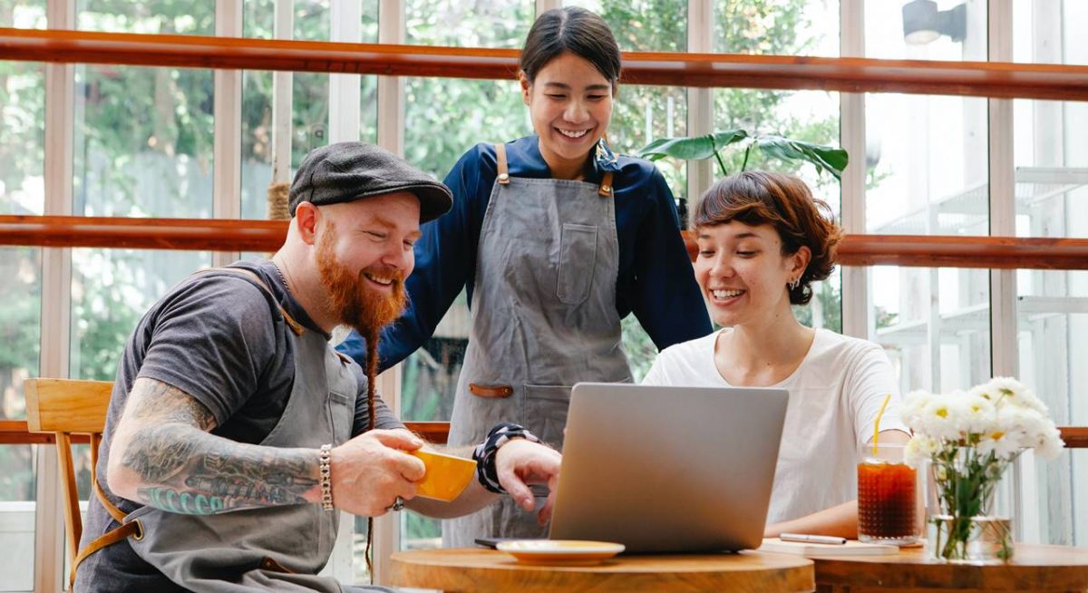 Tres compañeros de trabajo felices comunican con un ordenador, conectar con las personas marcas que Enamoran