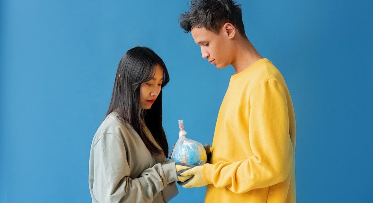 Una pareja sujeta la bola del mundo en una bolsa, sostenibilidad y bienestar Marcas que Enamoran